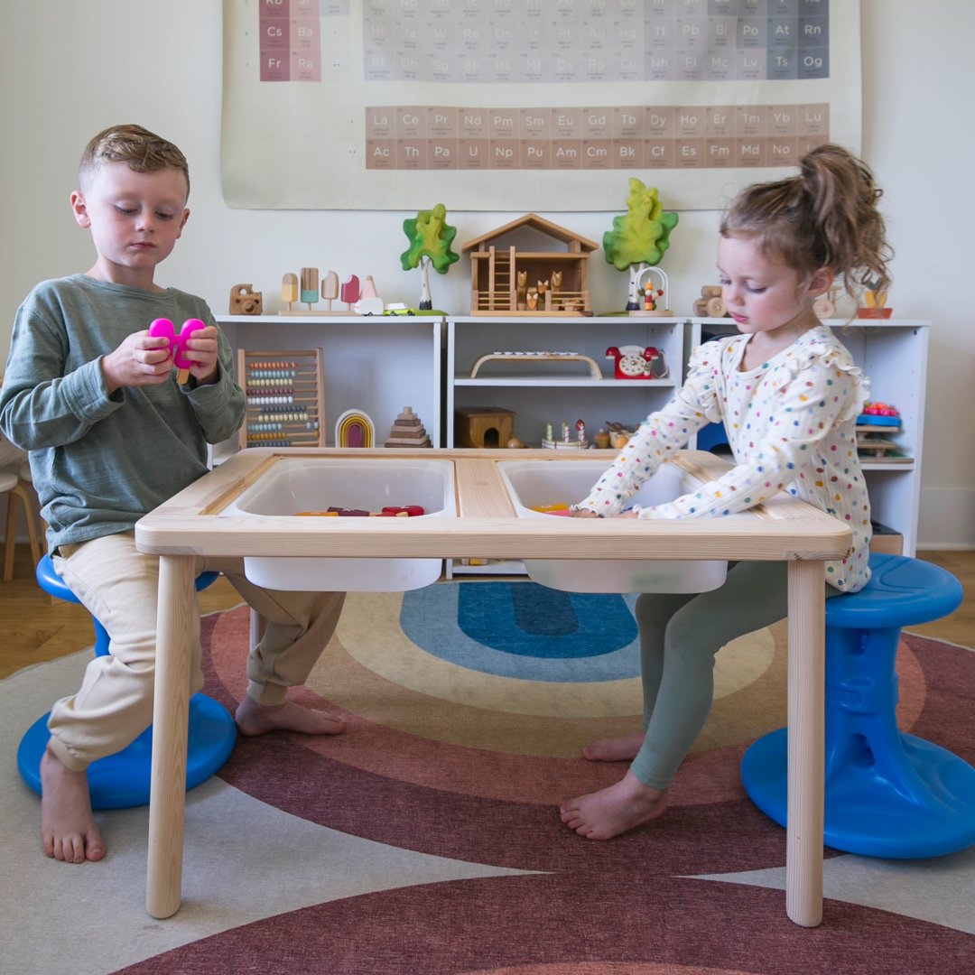 2 toddlers sitting at a sensory table sitting on wiggle chairs by simplay3 that promote sensory input and regulation