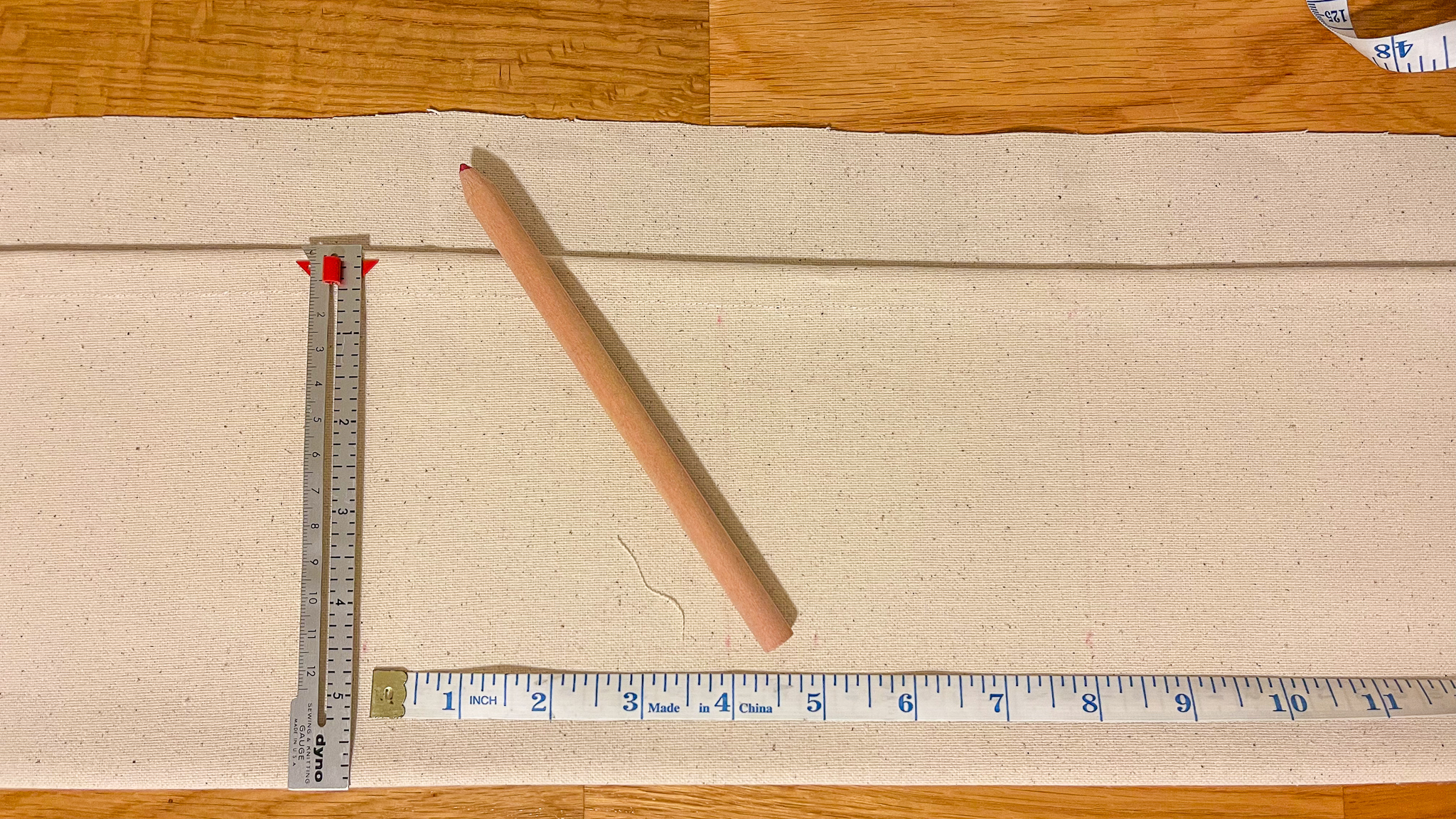 Simplay3's garden seat diy: hemmed fabric with pencil and measuring tape to get ready for a pocket