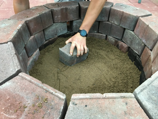 Lay and level paver sand at base of fire pit