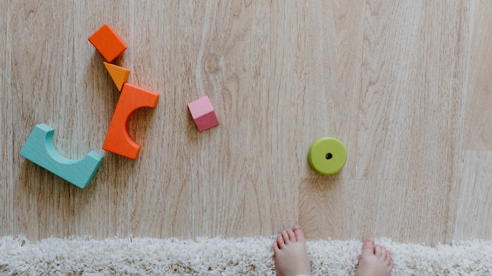 Simplay3's sensory sandbox ideas: an assortment of colorful blocks on the floor in front of a child's feet. 