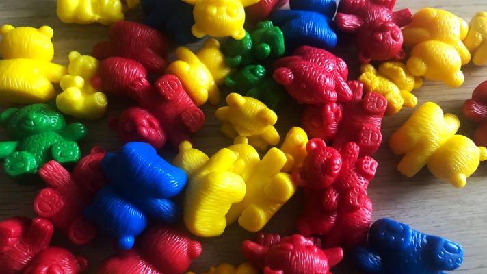 Simplay3's sensory sandbox ideas: red, yellow, blue and green counting bears in a pile of all sizes on a table 
