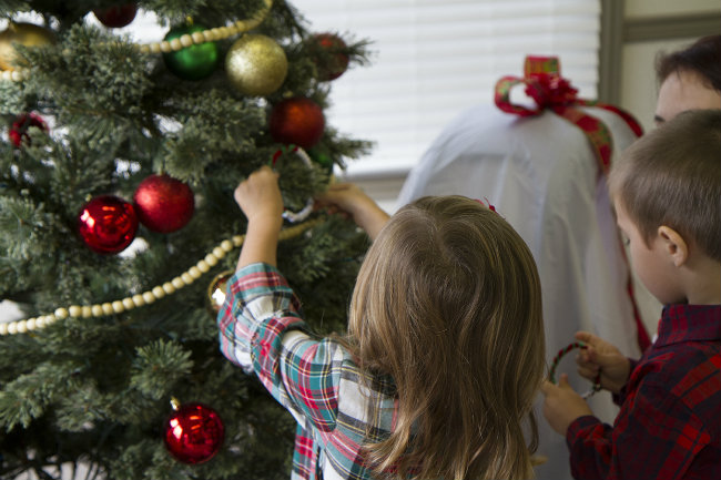 Toddlers hanging their homemade ornament on the tree